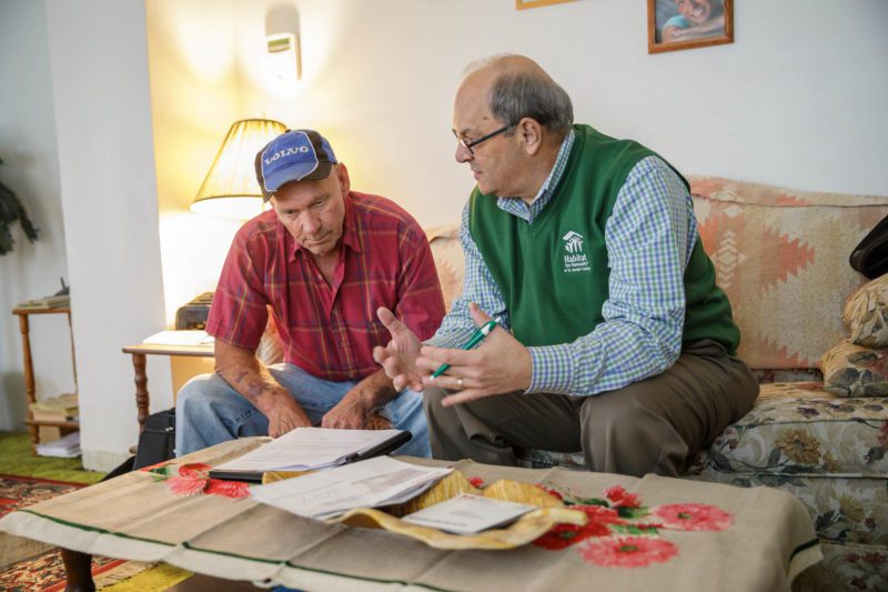 A Habitat for Humanity representative talks with a homeowner
