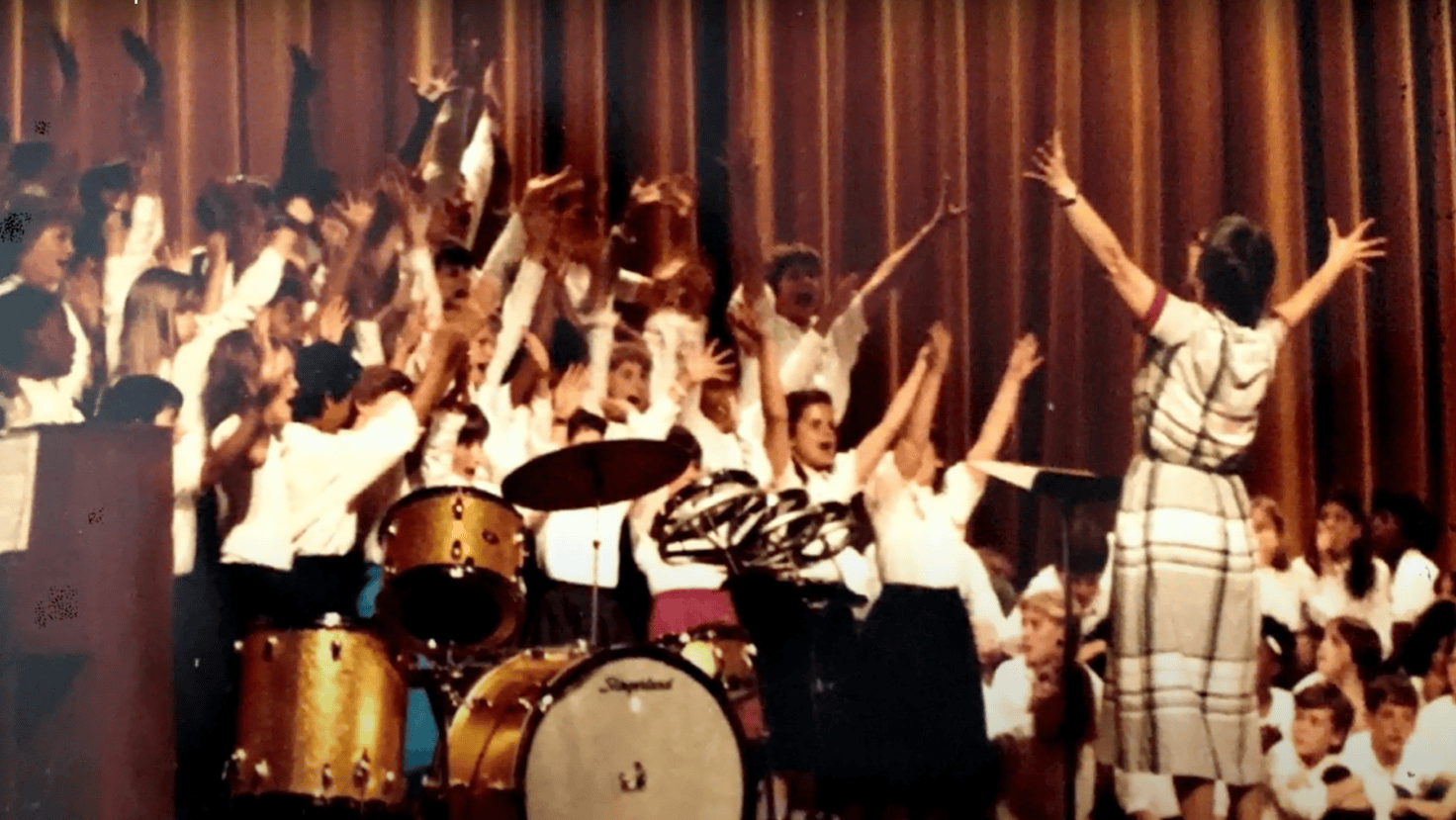 Following Mrs. Pollak's lead, choral students raise their arms along with their voices in this '80s-era photo.