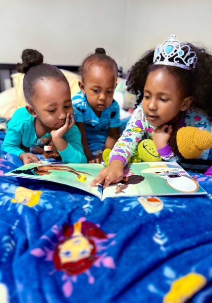 Photograph of three children enjoying a picture book