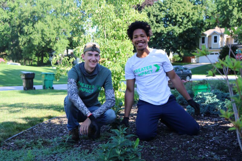 Two students work in the mulch with Greater Impact