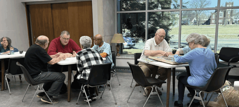 Seniors at the Real Services senior center enjoy time around the table together